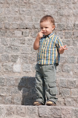 A  thoughtful boy in summer shirt is standing on the stone stairsの写真素材