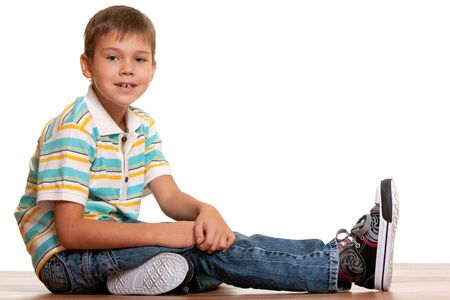 A portrait of a handsome boy sitting on the wooden floor; isolated on the white backgroundの写真素材