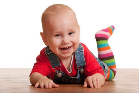 A portrait of a smiling little toddler in casual clothes lying on the wooden floor; isolated on the white backgroundの写真素材