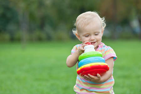 A little girl is holding toy pyramid while walking outsideの写真素材
