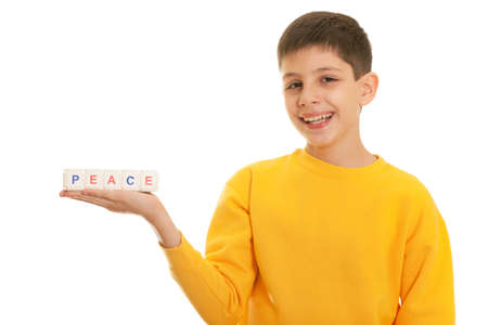 A closeup portrait of a smiling handsome boy in orange holding blocks PEACE on his hand; isolated on the white backgroundの写真素材