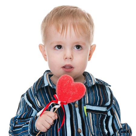 A handsome toddler with a red valentines heart; isolated on the white backgroundの写真素材