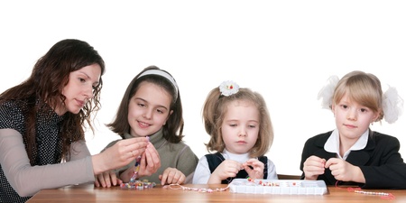 A teacher explains to three learners how to make handicraft in the classroom; isolated on the white backgroundの写真素材