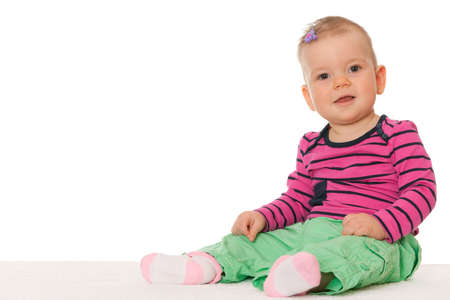 A smiling baby girl is sitting on the floor; isolated on the white backgroundの写真素材