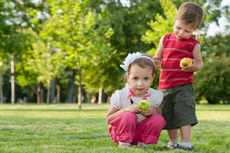 A little girl and a boy are holding applesの写真素材