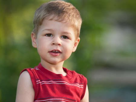 A smiling little boy is standing outdoorsの写真素材