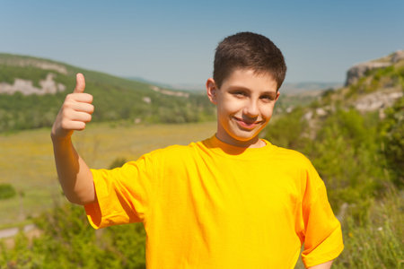 A smiling boy with his thumb up is standing against the Crimea valley; Ukraine