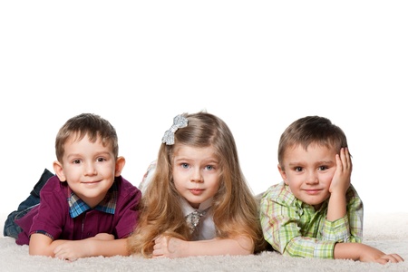 Three children are lying on the carpet together; isolated on the white backgroundの写真素材
