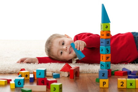 A cheerful little boy is playing on the carpetの写真素材