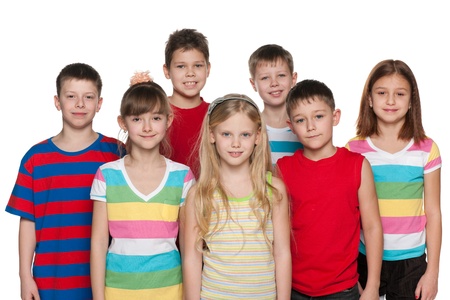 Group of seven children are standing on the white background; focus is on the central girlの写真素材