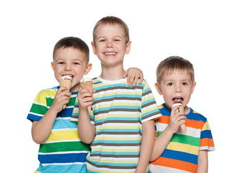 Three little boys are standing together and eating ice creamの写真素材