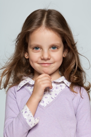 Portrait of a pretty smiling little girl on the grey backgroundの写真素材