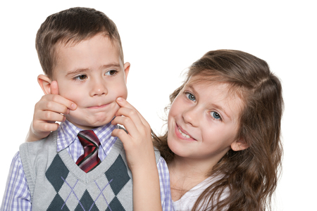 A cheerful sister makes her brother smile on the white backgroundの写真素材
