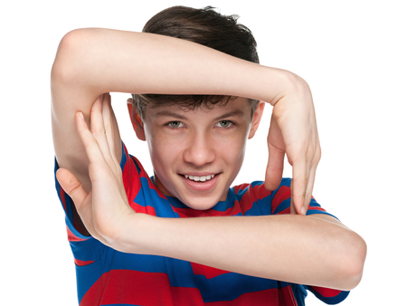 A portrait of a cheerful teen boy holding his hands like a window frame on the white backgroundの写真素材