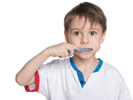 Portrait of a little boy brushing his teeth against the white backgroundの写真素材