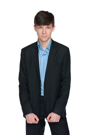 A portrait of a confident teen boy in a black suit on the white backgroundの写真素材