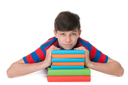 A teenager boy is lying on the floor near the pile of books on the white backgroundの写真素材
