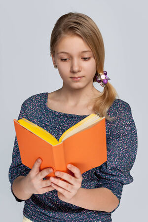 A pretty girl reads book against the gray backgroundの写真素材