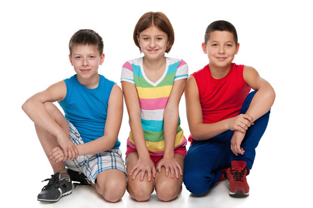 A group of three happy children are sitting on the white backgroundの写真素材