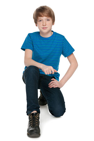 A fashion preteen boy is sitting on the white backgroundの写真素材