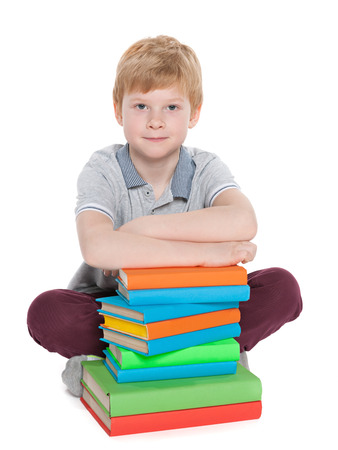 A clever young boy with a pile of books on the floorの写真素材
