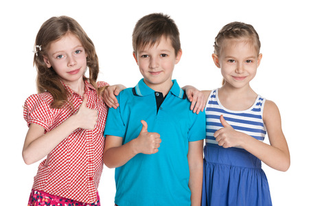 Portrait of a group of three cheerful children holding his thumbs up on the white backgroundの写真素材
