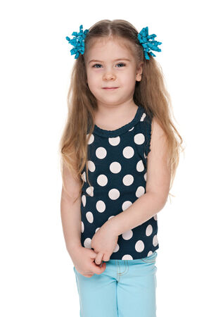 A pretty little girl is standing against the white backgroundの写真素材