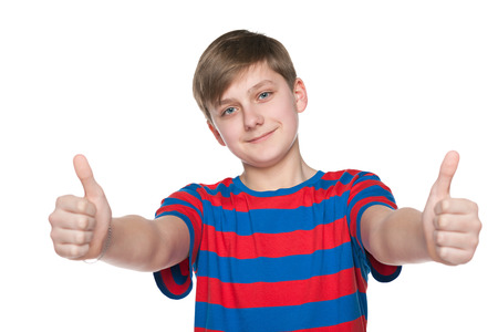 A teenager boy holds his thumbs up on the white backgroundの写真素材