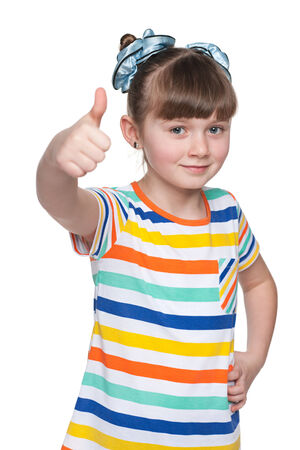 AAn adorablel young girl holds her thumbs up against the white backgroundの写真素材