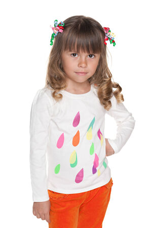 A serious preschool girl is standing against the white backgroundの写真素材