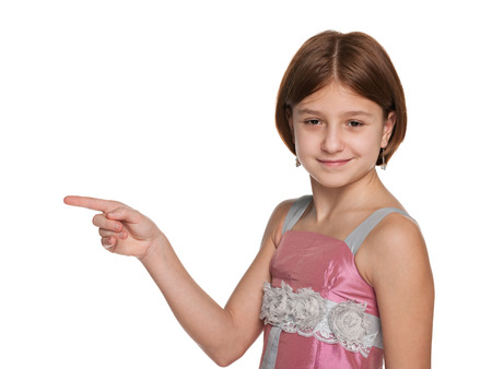 A preteen girl shows her finger to the side on the white backgroundの写真素材