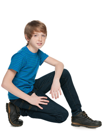 A handsome preteen boy sits on the white backgroundの写真素材
