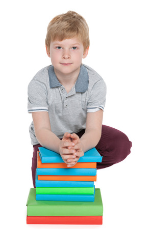 A clever little boy with a pile of books on the floorの写真素材
