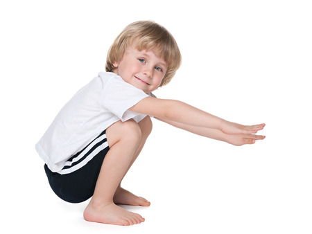 A cute preschool boy performs exercises on the white backgroundの写真素材
