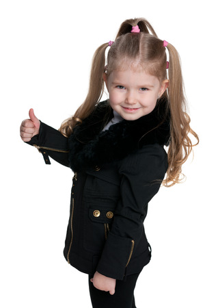 A little girl in the black coat holds her thumb upの写真素材