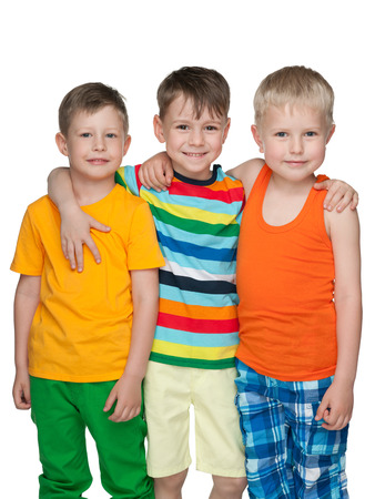 Three happy little boys are standing together against the white backgroundの写真素材