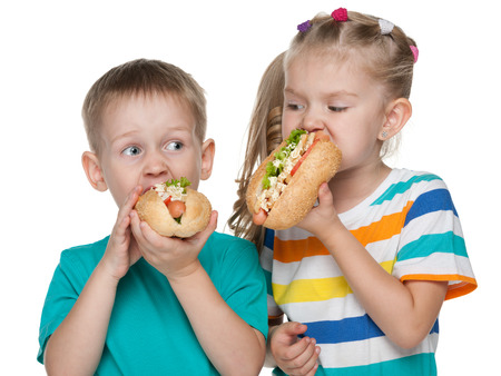 Two children with hot dogs on the white backgroundの写真素材