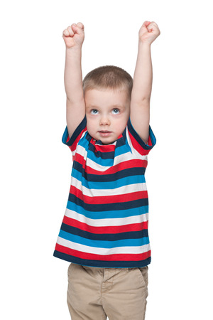 A cute little boy shows how he is tall against the white backgroundの写真素材