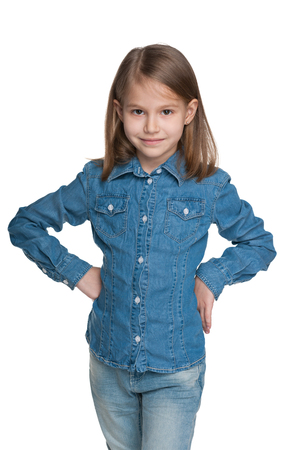 A fashion lovely little girl is standing against the white backgroundの写真素材