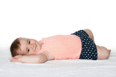 A smiling infant girl is lying on the white towelの写真素材