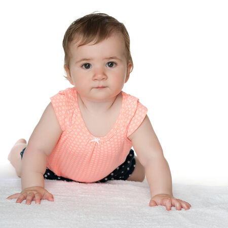 A cute baby girl is crawling on the white carpetの写真素材