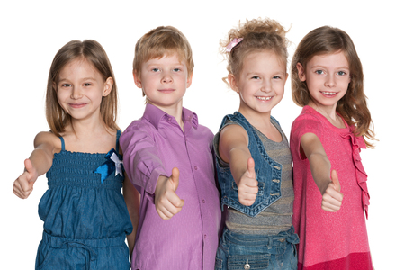 Portrait of a group of four happy children holding their thumbs up on the white backgroundの写真素材