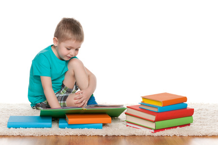 A clever little boys with books sits on the floorの写真素材