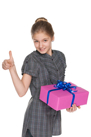 A preteen girl with a gift box holds her thumb up on the white backgroundの写真素材