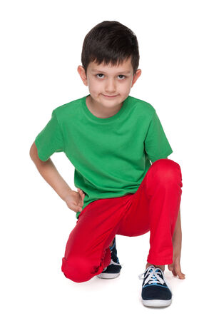 A handsome young boy in the green shirt is sitting on the white backgroundの写真素材
