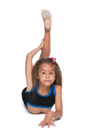 A pretty little gymnast does exercises on the white backgroundの写真素材
