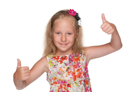 A cute little girl holds her thumbs up on the white backgroundの写真素材