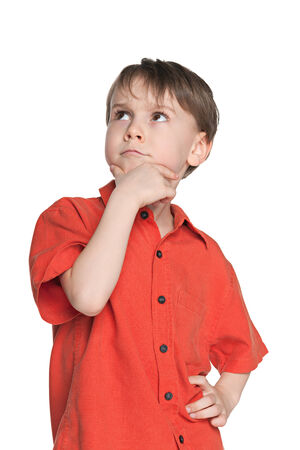 A serious little boy in a red shirt on the white backgroundの写真素材