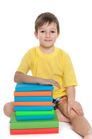 A little boy in a yellow shirt near books on the floorの写真素材