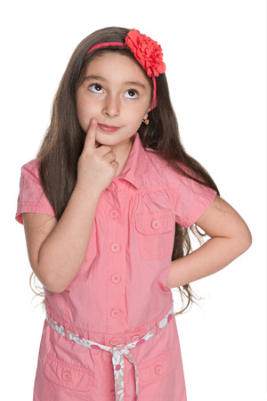 A pensive pretty little girl looks up on the white backgroundの写真素材